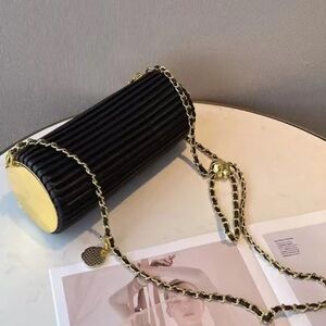 Pleated black cylinder bracelet bag with gold hardware
